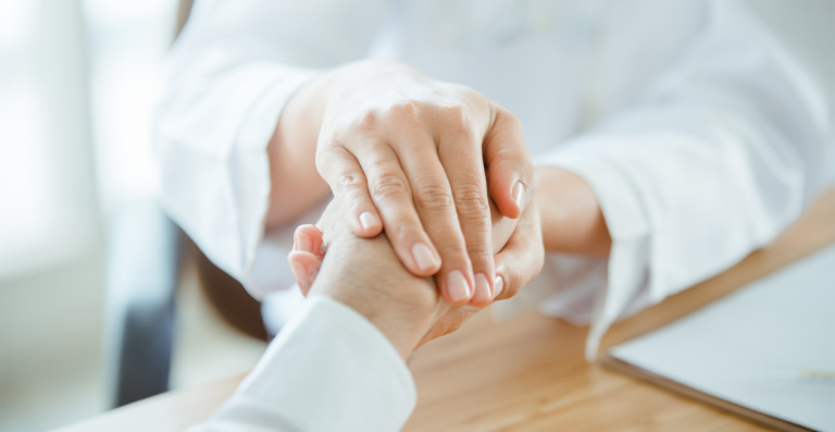 Healthcare professional holding patient's hand during consultation
