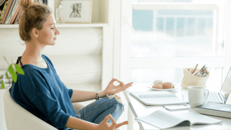 Woman meditating at desk in home office setting
