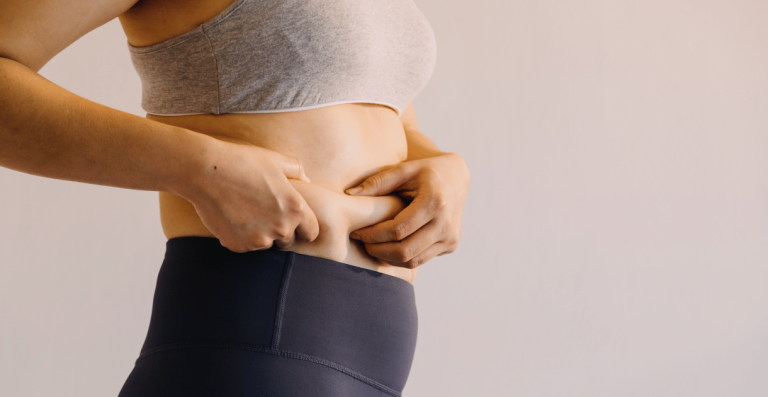 Woman holding abdominal fat related to metabolic slowdown