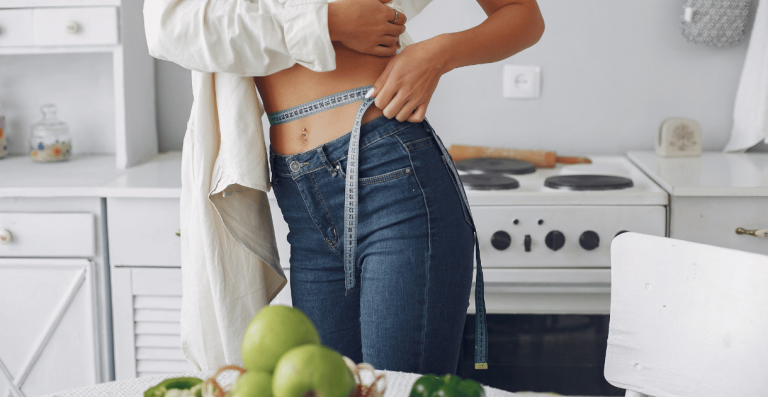 Woman measuring waist due to hormonal weight changes