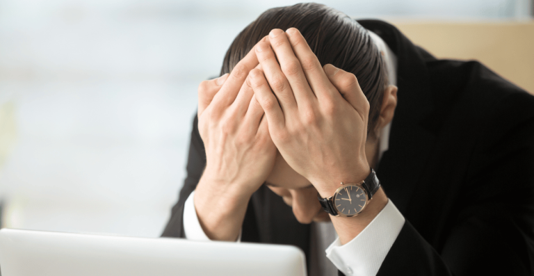 Man feeling stressed and overwhelmed while working at laptop
