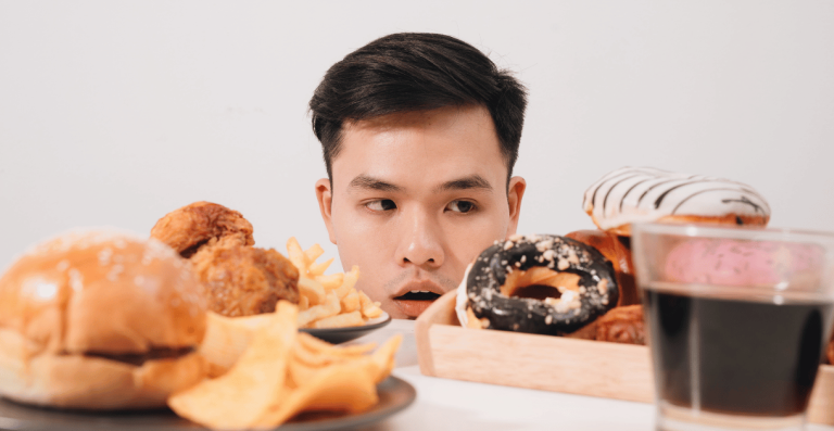 Man looking at fast food and sweets linked to food cravings