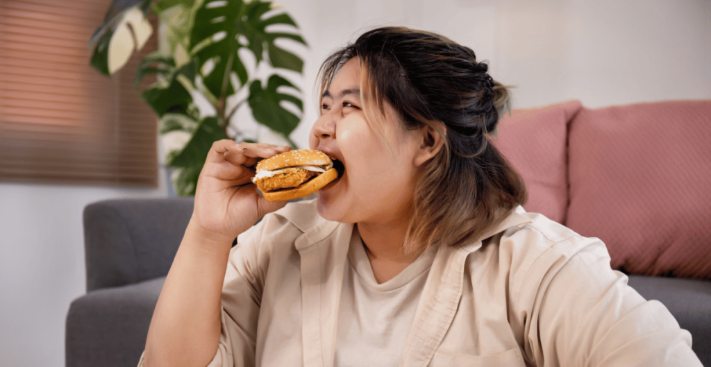 Woman eating a burger at home representing frequent hunger