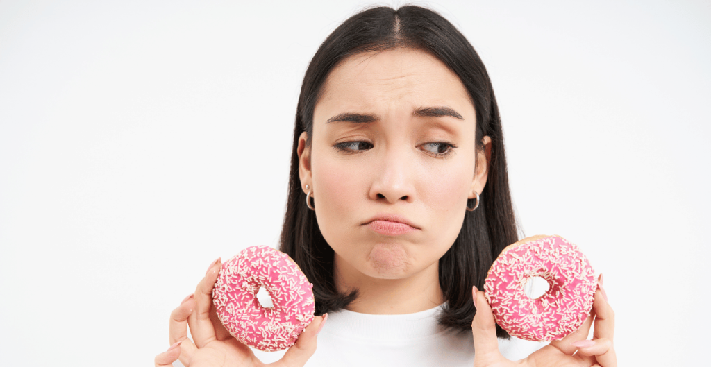 Woman holding donuts looking unsure about weight loss choices